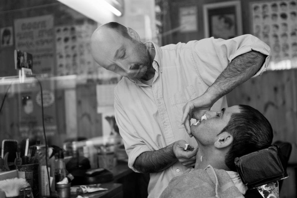 Un barbero afeita a su cliente