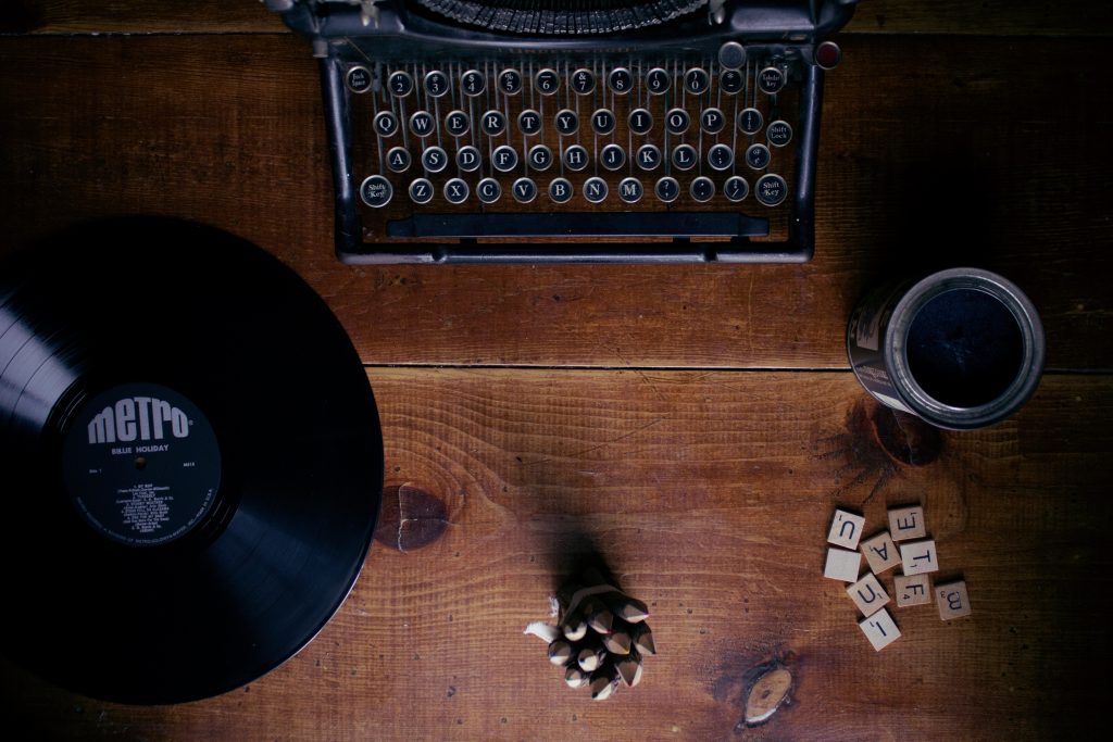 Máquina de escribir, disco de vinilo y unas piezas (letras) de scrabble.